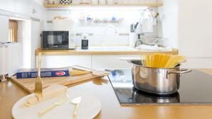 A kitchen with a pot of spaghetti, a cutting board, a box of pasta, and a knife on a wooden table. - Cicciobello Lux Apartment with stunning sea view (Baošići)