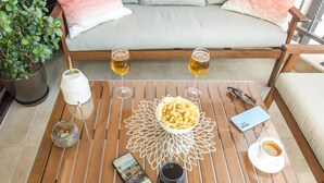 A wooden table with a bowl of snacks, two glasses of beer, a smartphone, a cup of coffee, and a pair of sunglasses. - Cicciobello Lux Apartment with stunning sea view (Baošići)