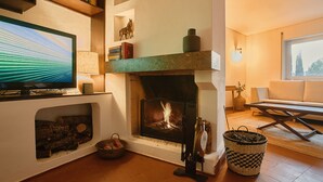 A cozy living room with a fireplace, a television, and a comfortable seating area. - Perfect for quiet vacation with family and friends (Setúbal)