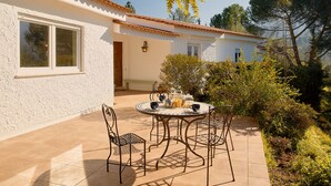 A patio with a round table and chairs, a small window, and a door. - Perfect for quiet vacation with family and friends (Setúbal)