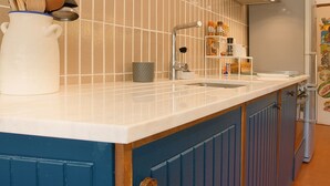 A kitchen with a white countertop, blue cabinets, and a tiled backsplash. - Perfect for quiet vacation with family and friends (Setúbal)