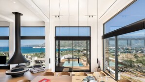 Un espace de restauration moderne, doté d’une grande table, de chaises et offrant une vue sur l’océan et le paysage urbain grâce à de larges fenêtres.