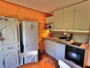 A compact kitchen with a refrigerator, microwave, stove, and dishwasher.