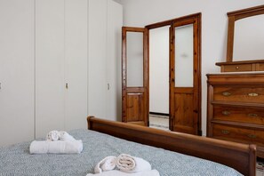 Un dormitorio con cama, cómoda de madera, armario y espejo.