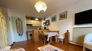 Un espacio habitable compacto con comedor, cocina y televisor montado en la pared.