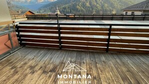 Una terraza de madera con baranda de metal que da a un paisaje montañoso.