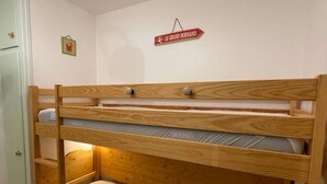 Una cama litera con estructura de madera y un cartel encima que dice "LE GRAND BORNAND".
