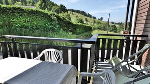 Ein Balkon mit Tisch und Stühlen mit Blick auf einen grünen Hügel.