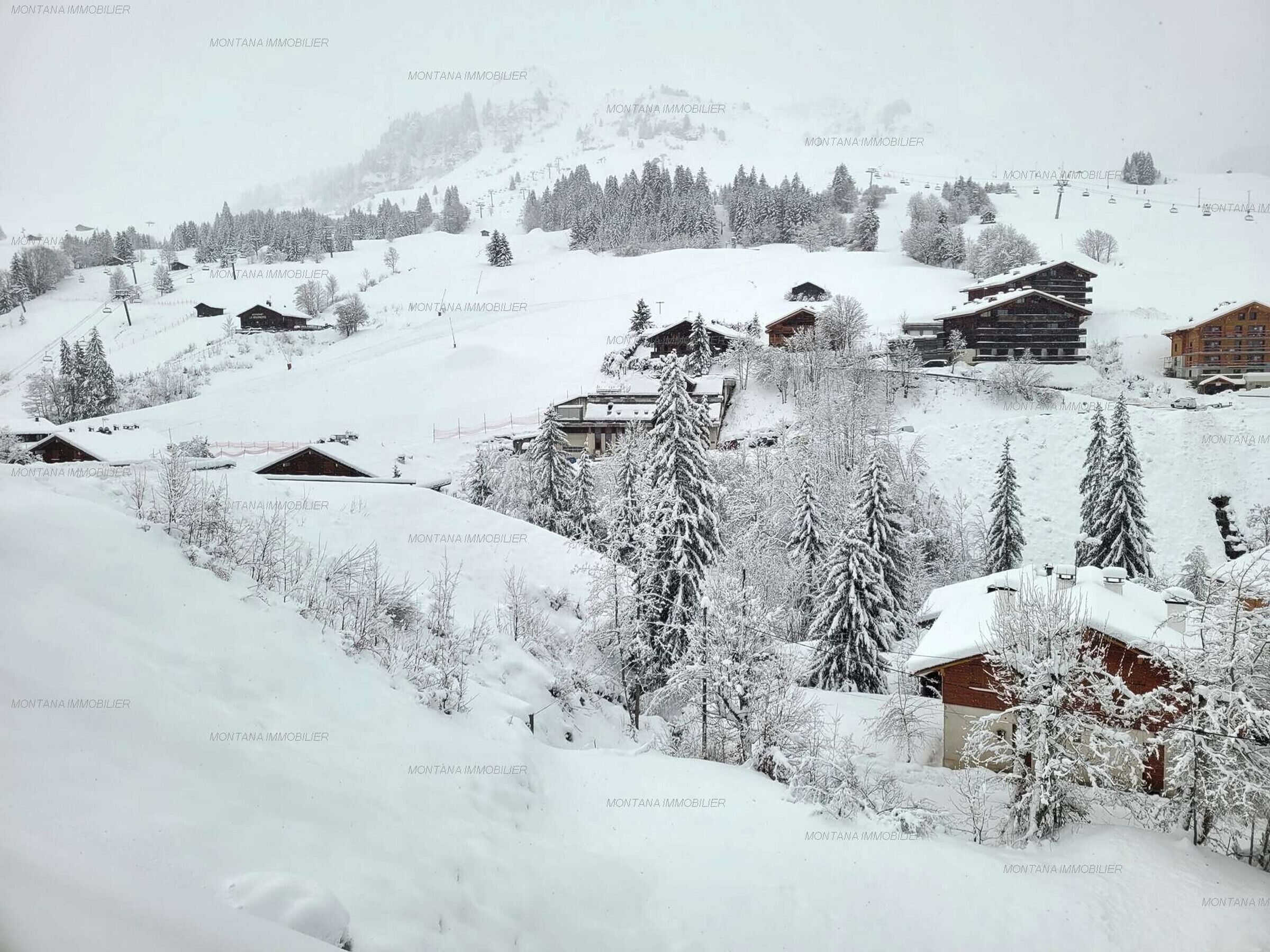 A snow-covered village with wooden buildings and a ski lift in the background.