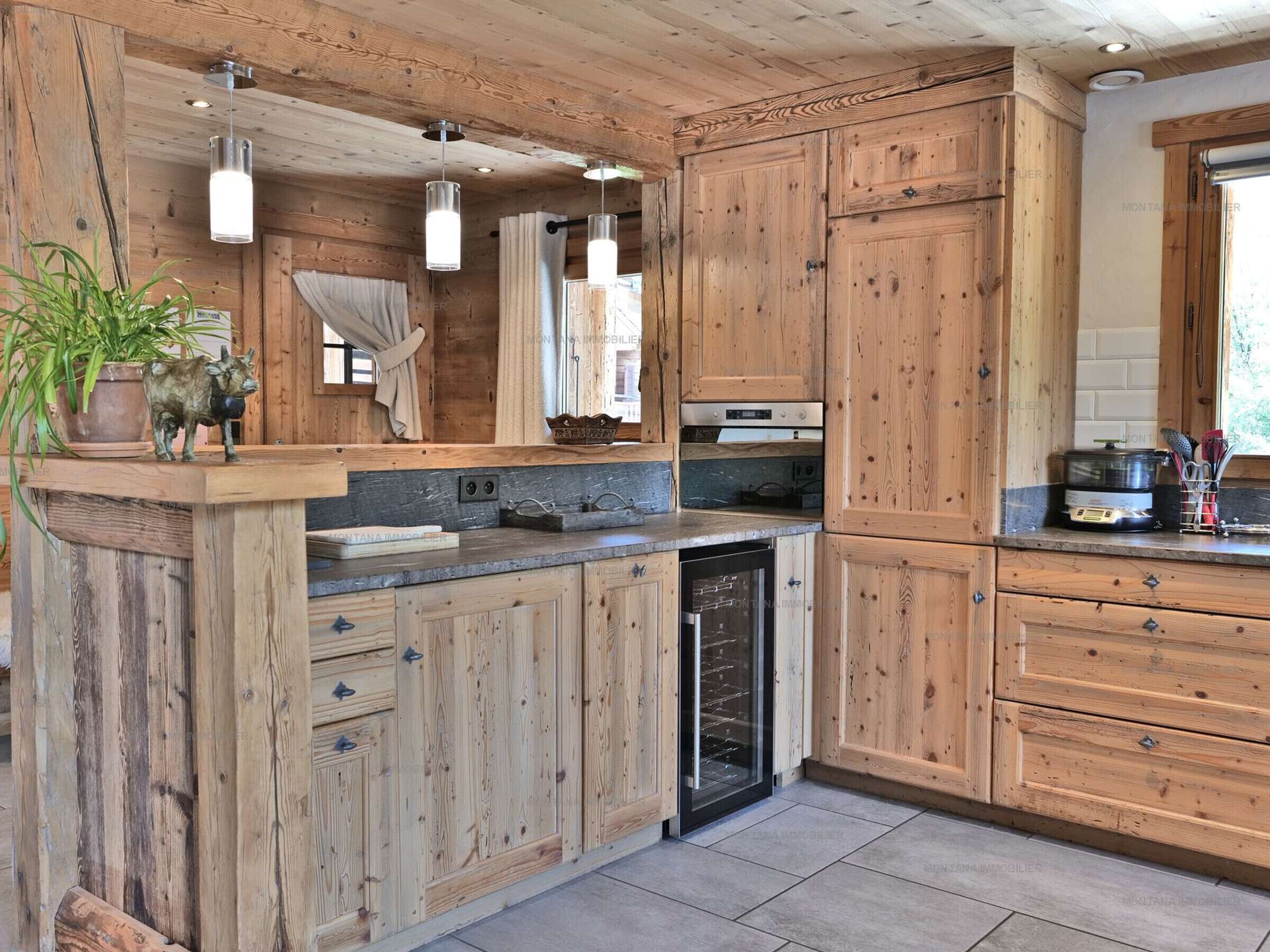 Une cuisine avec des meubles en bois, un lave-vaisselle encastré et des luminaires suspendus.
