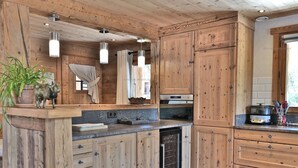 A kitchen with wooden cabinets, a built-in dishwasher, and pendant lights.