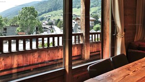 A wooden balcony with a view of a village and mountains.