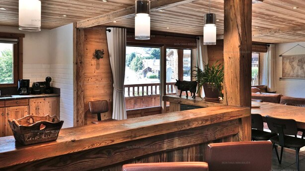 A rustic interior with wooden beams, a bar area, and seating.