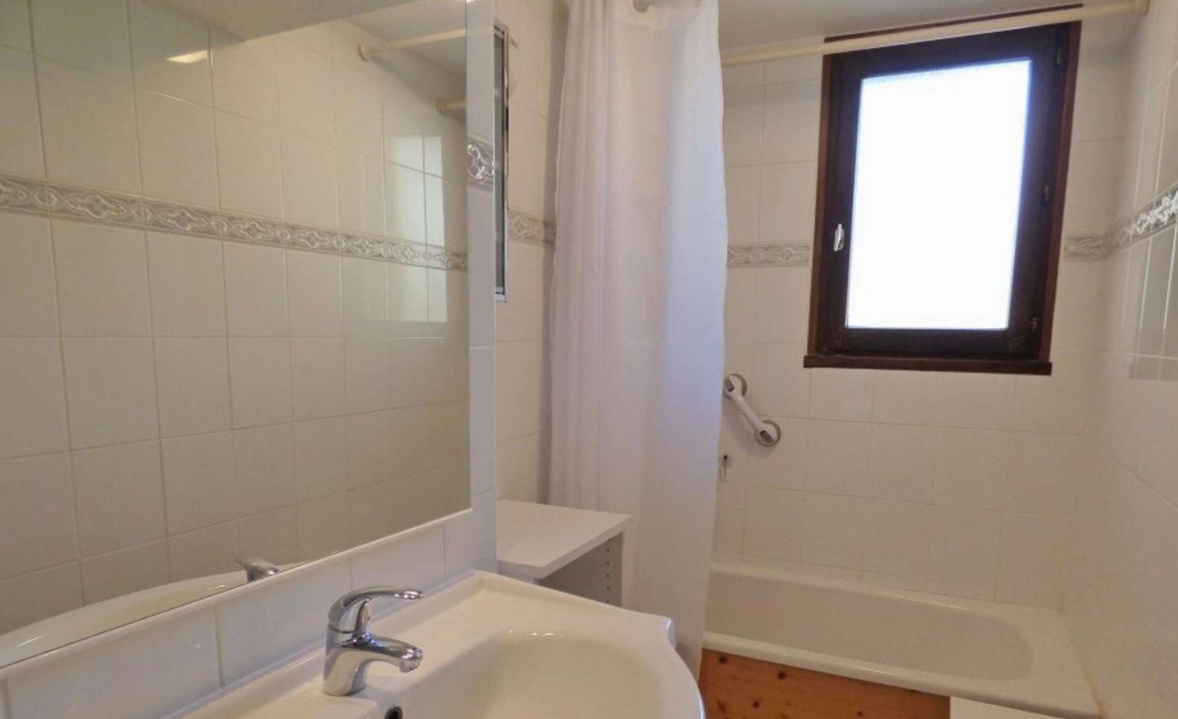 A bathroom with a sink, mirror, and a window.