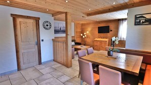 A wooden interior with a dining area, a clock, and a television. - Charming 3-room renovated with sauna and jacuzzi for 6 in Grand-Bornand (Le Grand-Bornand)