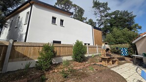 Een modern huis met twee verdiepingen, een witte gevel, een houten terras en een terras van baksteen.