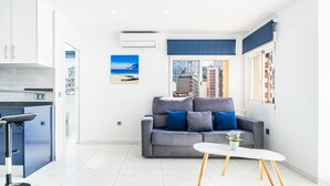 A modern living room with a grey sofa, a white coffee table, and a city view through large windows. - Don Paco 12-B Deluxe Apartment Levante Beach (Benidorm)