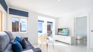 A modern living room with a grey sofa, a TV, and a balcony with a view of the sea. - Don Paco 12-B Deluxe Apartment Levante Beach (Benidorm)