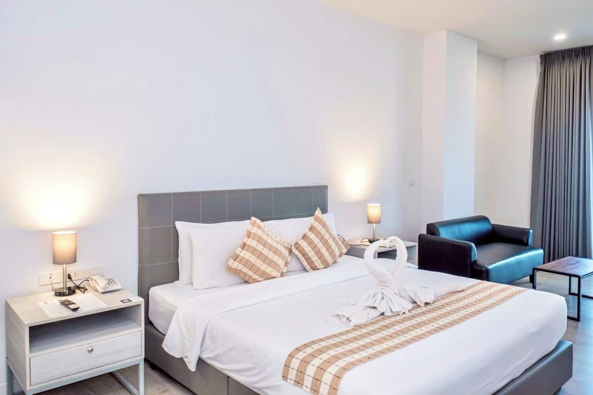 A hotel room with a bed, bedside tables, a chair, and a lamp.