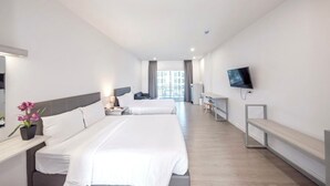 A hotel room with two beds, a TV, a desk, and a balcony view. - GRAND PA Hotel&Resort Lamphun Chiang Mai (Lamphun)