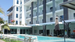 A modern hotel with a swimming pool, outdoor seating, and balconies. - GRAND PA Hotel&Resort Lamphun Chiang Mai (Lamphun)