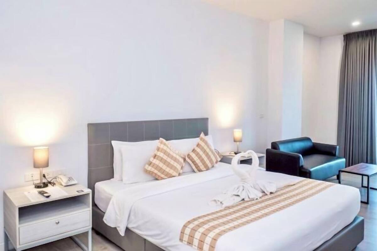 A hotel room with a bed, bedside tables, a chair, and a desk.