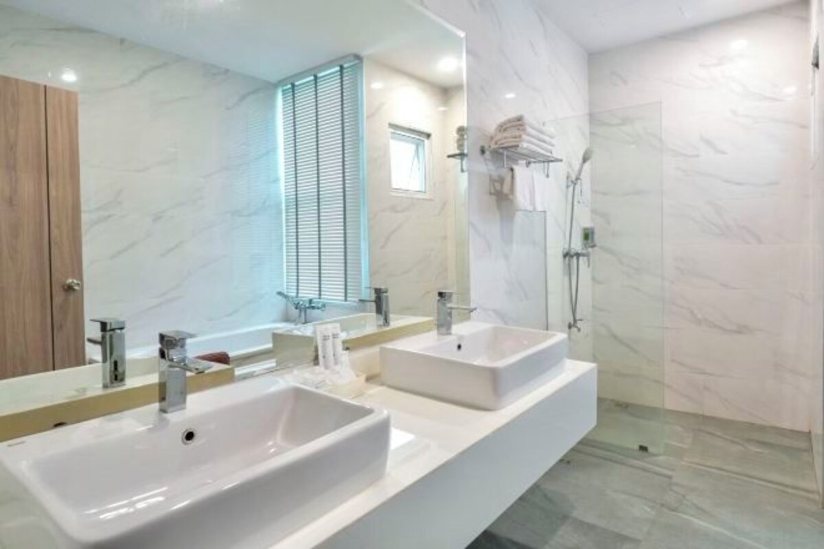 Un baño moderno con dos lavamanos, un espejo grande y una zona de ducha.