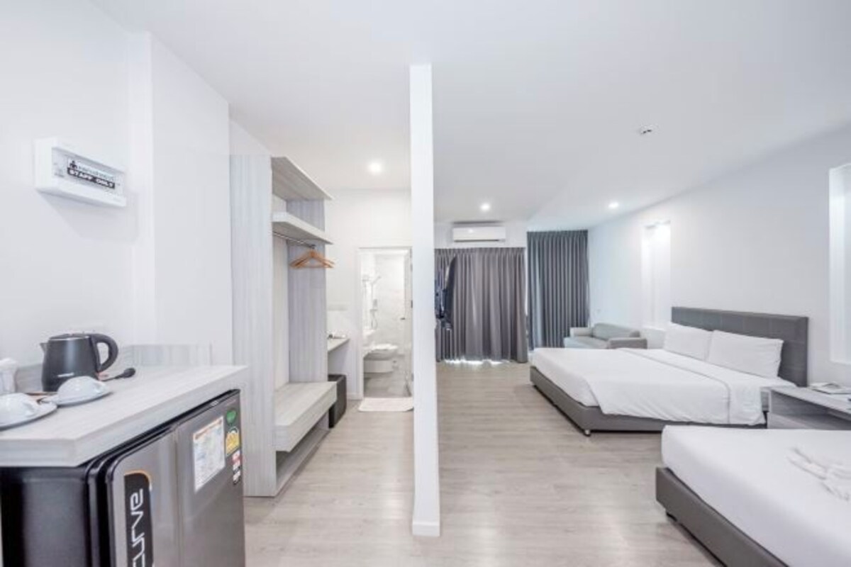 Una habitación de hotel moderna con kitchenette, cama, escritorio y baño.