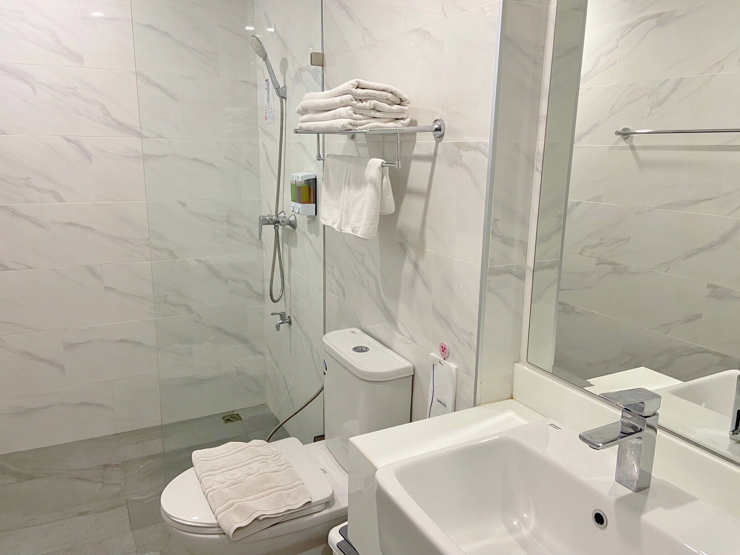A modern bathroom with a glass-enclosed shower, a toilet, and a sink with a mirror.