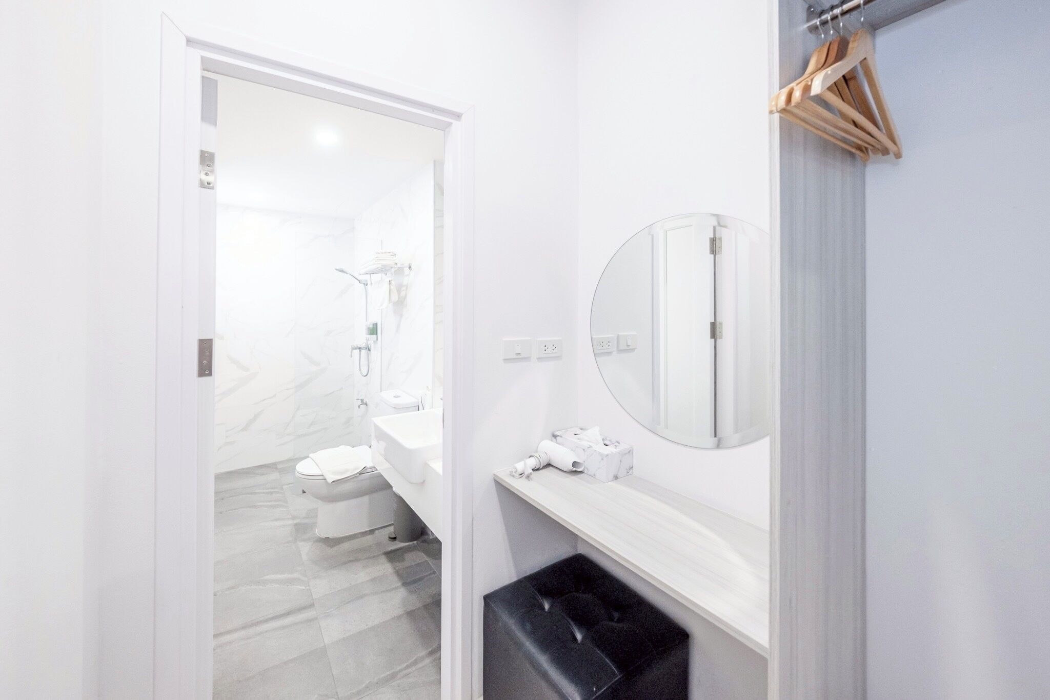 A modern bathroom with a white sink, mirror, and a black trash bin.