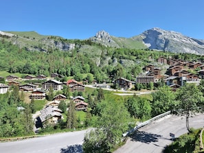 A mountain resort with chalet-style lodges, a winding road, and a backdrop of rocky mountains.