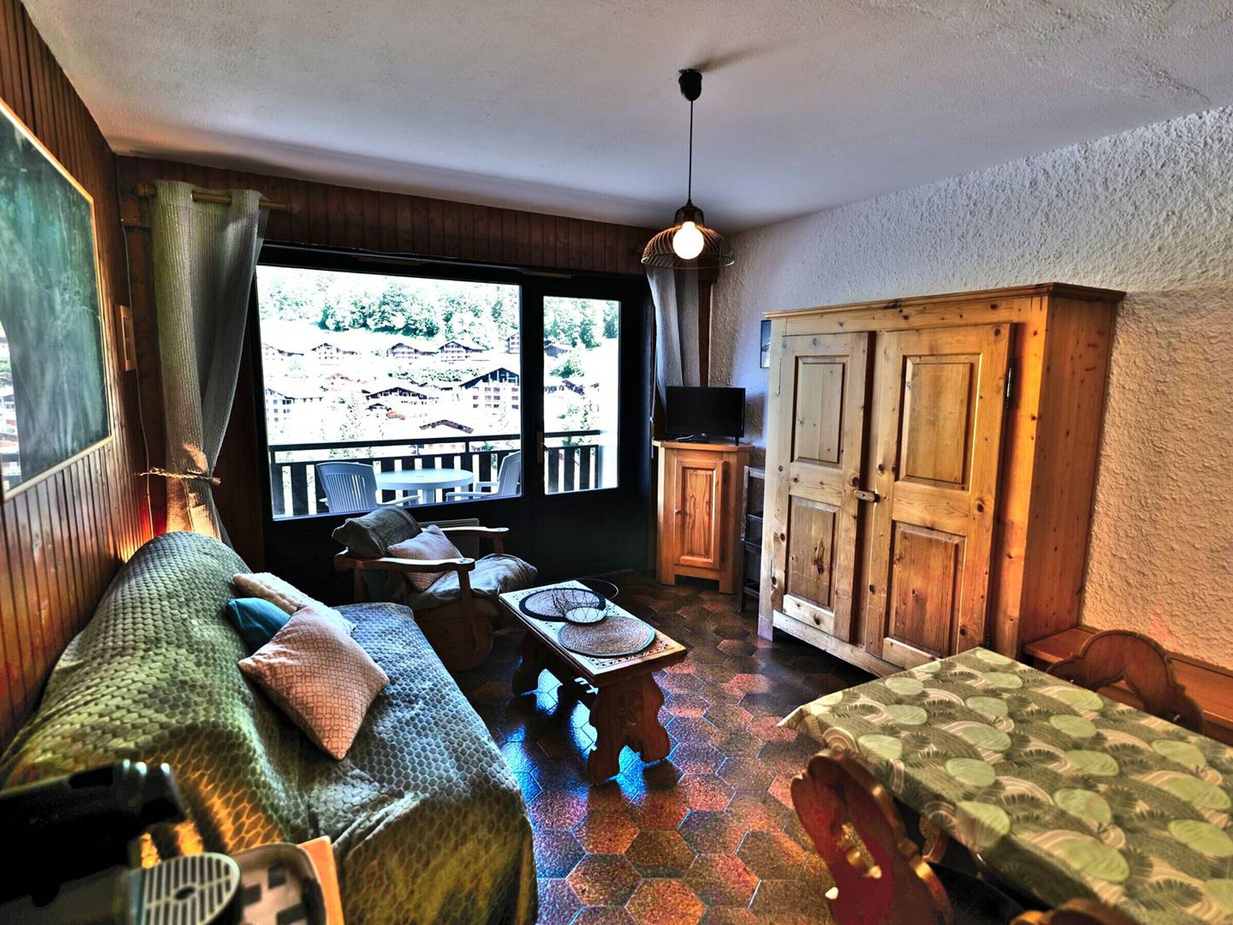Et hyggeligt værelse med sofa, bord, skab og fjernsyn.