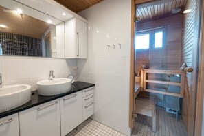 A modern bathroom with two sinks, a large mirror, and a shower area.