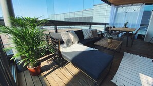 A wooden deck with a sofa, a table, and chairs. There is a potted plant and a white rug. - 2ndhomes Kamppi Center Apartment 9 (Helsinki)