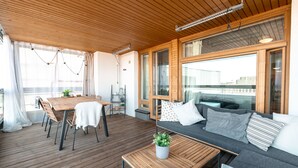 A wooden deck with a dining table and chairs, a sofa with cushions, and a small table with a plant. - 2ndhomes Kamppi Center Apartment 9 (Helsinki)