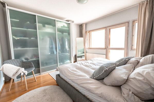 Een slaapkamer met een bed, een stoel, een kledingkast en een raam.
