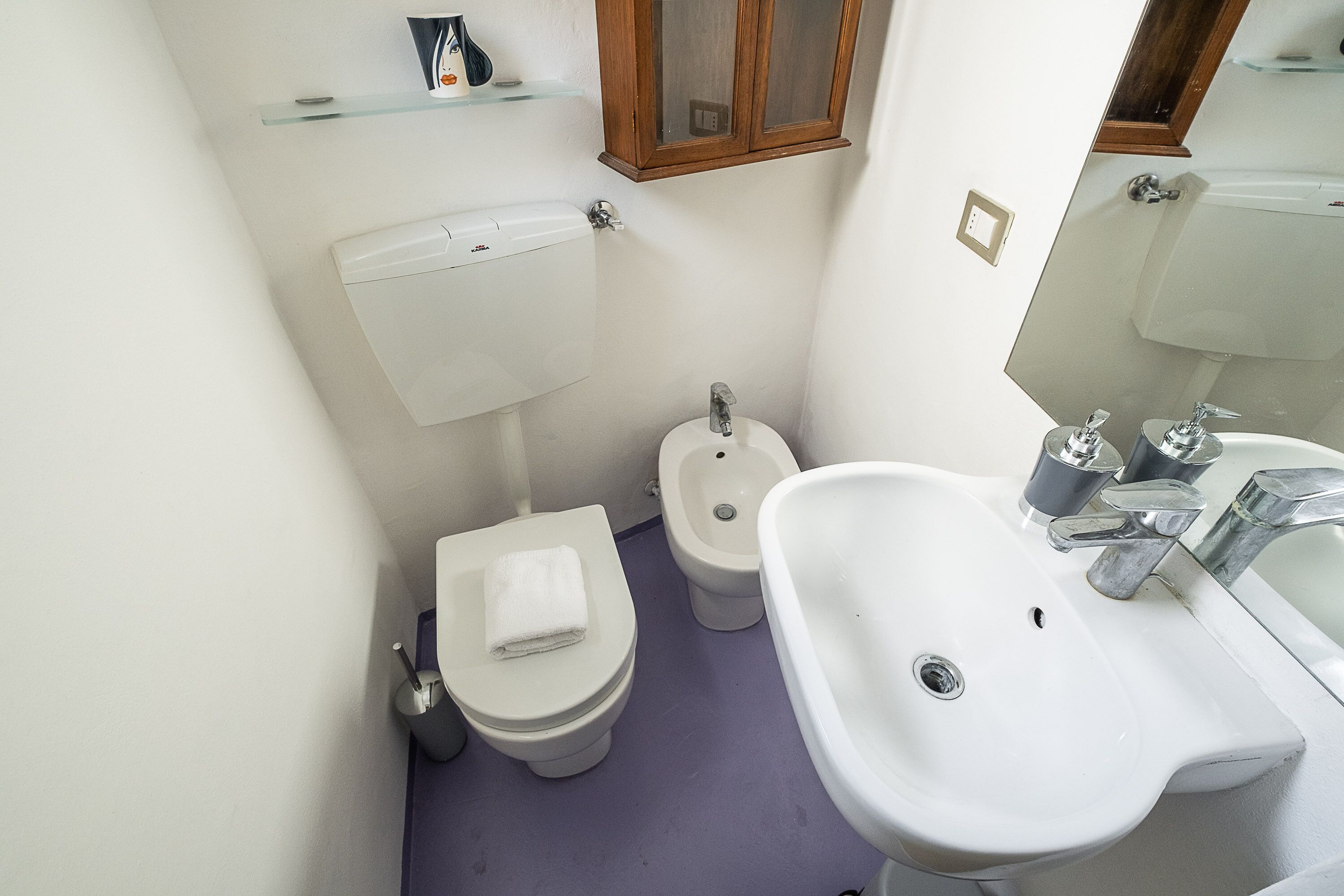 A compact bathroom with a toilet, bidet, and a sink.