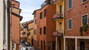 A narrow street lined with multi-story buildings, featuring balconies and ground-floor shops. - A pochi passi da Piazza Maggiore by Wonderful Italy (Bologna)