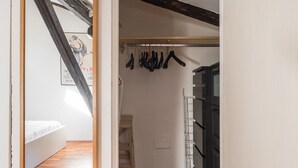 A hallway with a wooden floor, a coat rack, and a staircase leading to a bedroom.