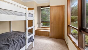 A bunk bed room with a window and a wooden door.