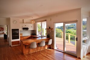 A modern kitchen with a wooden island, bar stools, and a view of a deck.