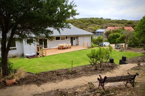 A residential property with a well-maintained lawn, a wooden deck, and a house with a grey roof. - Cowallinga (Fairhaven)