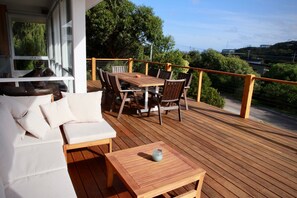 A wooden deck with a sofa, chairs, and a table. - Cowallinga (Fairhaven)