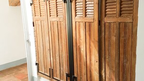 Un ensemble de portes coulissantes en bois, dotées de poignées en métal, un revêtement de sol en carrelage blanc et un cadre de porte visible.