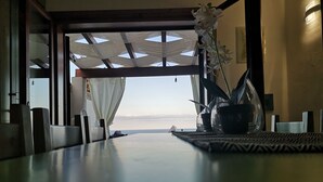 A dining area with a view of the sea, a table with a potted plant, and a ceiling with a geometric pattern. - SWEET HOME CAMILLA Costa Rei with Panoramic Terrace 300 meters from the beach (Costa Rei)
