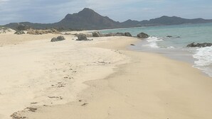A beach with clear skies, sandy shore, and rocky outcrops. - SWEET HOME CAMILLA Costa Rei with Panoramic Terrace 300 meters from the beach (Costa Rei)