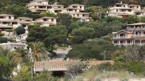 A hillside residential area with multiple two-story houses, some with balconies, surrounded by dense greenery and trees. - SWEET HOME CAMILLA Costa Rei with Panoramic Terrace 300 meters from the beach (Costa Rei)
