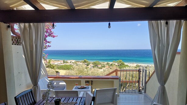 A covered outdoor dining area with a view of the sea and beach. - SWEET HOME CAMILLA Costa Rei with Panoramic Terrace 300 meters from the beach (Costa Rei)