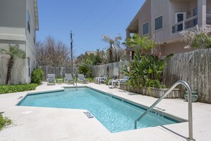 A rectangular swimming pool with a 3ft 6in depth marker, surrounded by lounge chairs and a wooden fence. - Renovated Coastal Condo • Community Pool • 3 Min Walk to Beach (South Padre Island)