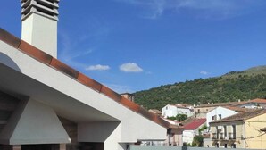 Une terrasse sur le toit avec un espace barbecue en briques, un banc et une vue sur une ville située sur une colline.